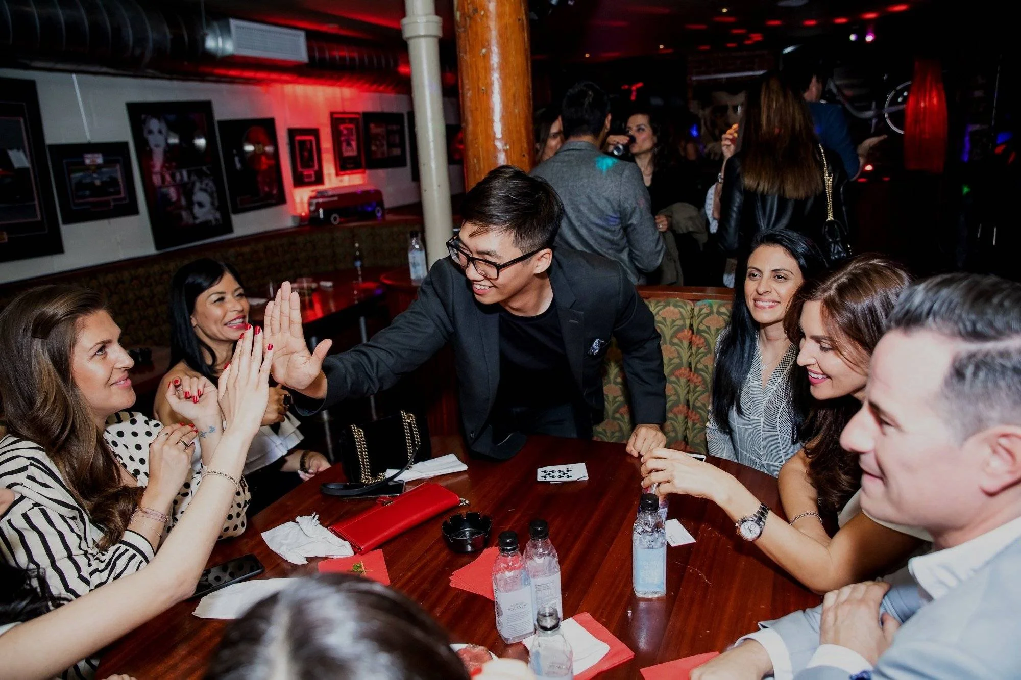 Montreal magician Bao Hoang captivates a group with close-up magic during a corporate party, while others enjoy the event in the background.