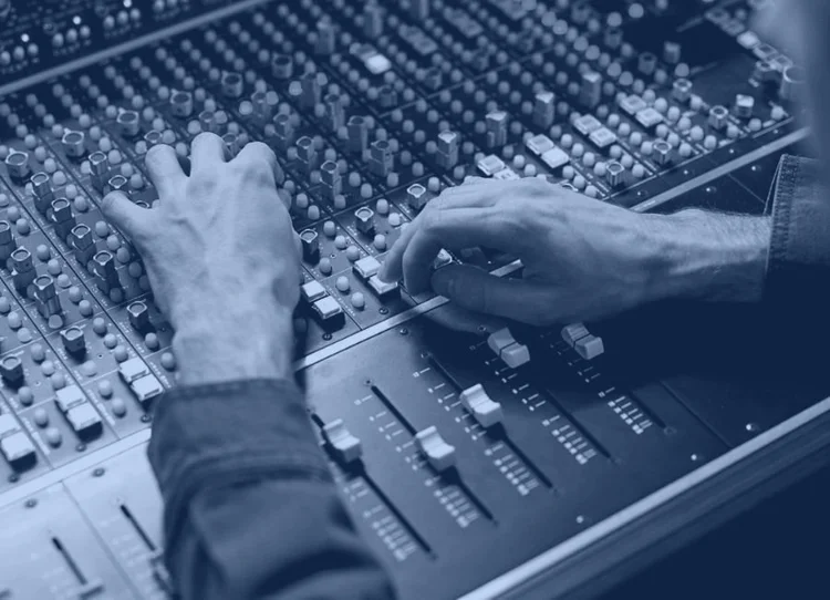 Hands adjusting the faders on a mixing desk