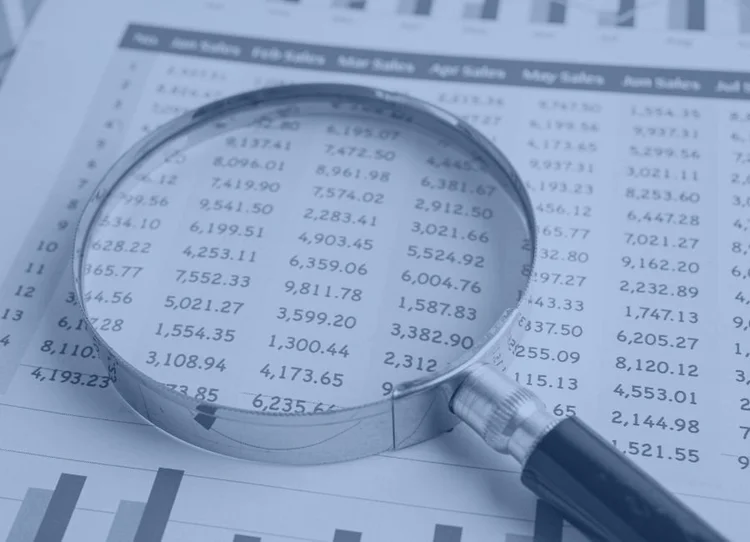Magnifying glass over a printed financial spreadsheet