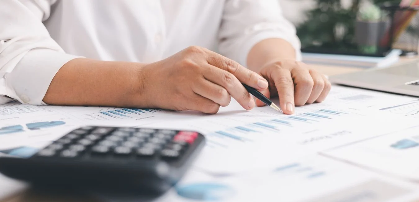 Printed financial forecasting reports with budget and revenue charts on a desk