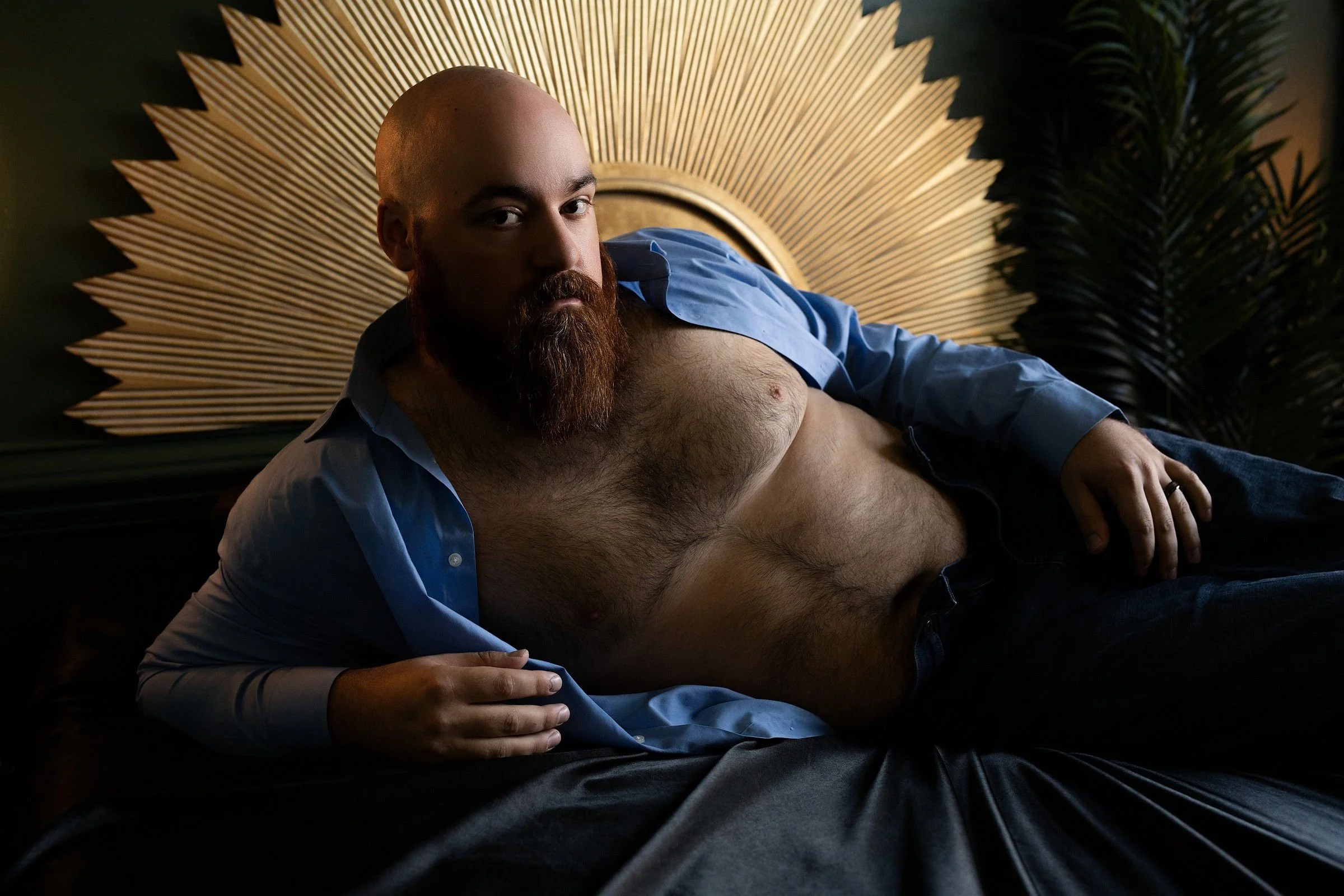 Man posing in a blue shirt during a polished male boudoir photography session in Arkansas