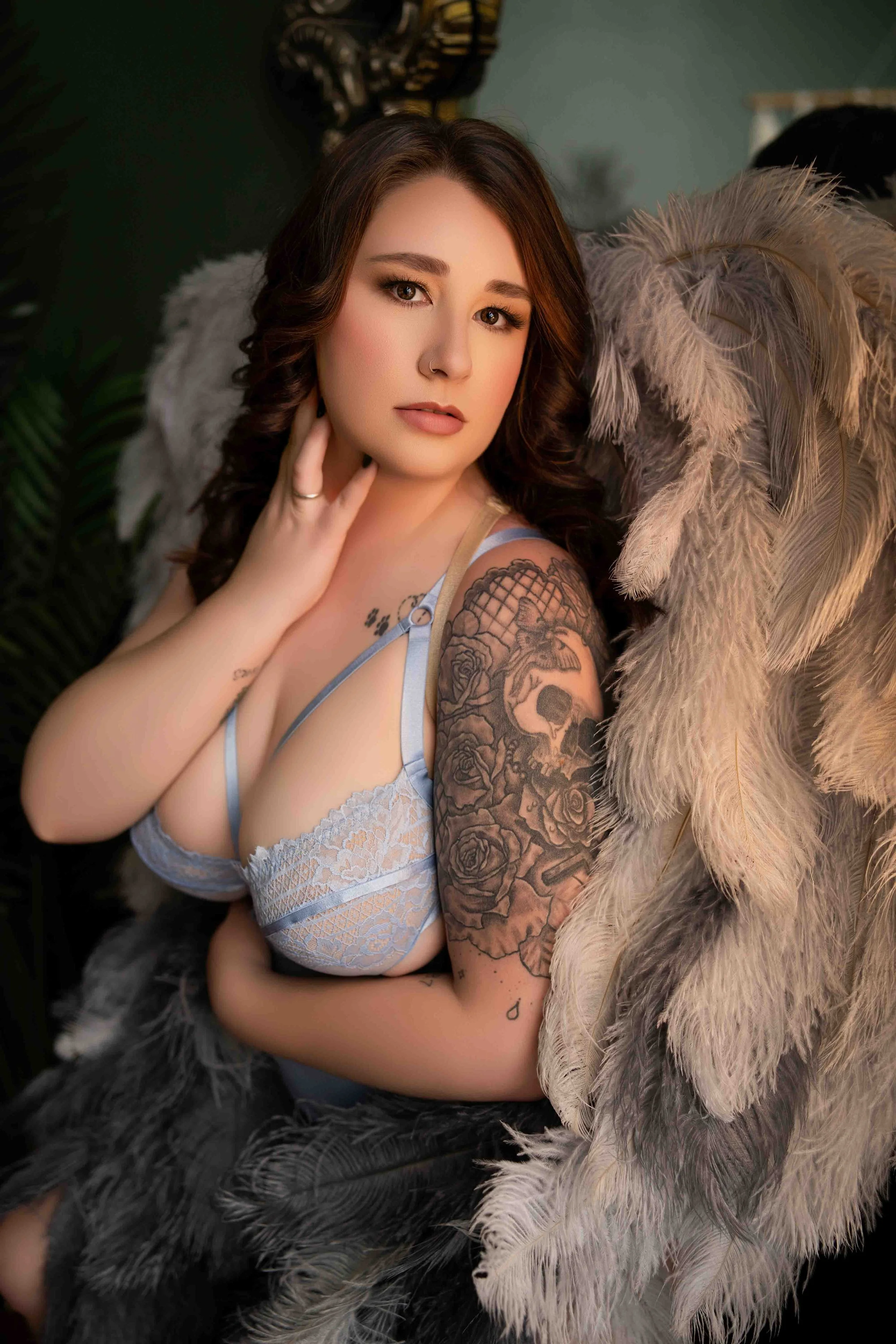 Woman posing confidently in blue lace lingerie with angel wings in a softly lit Arkansas boudoir studio