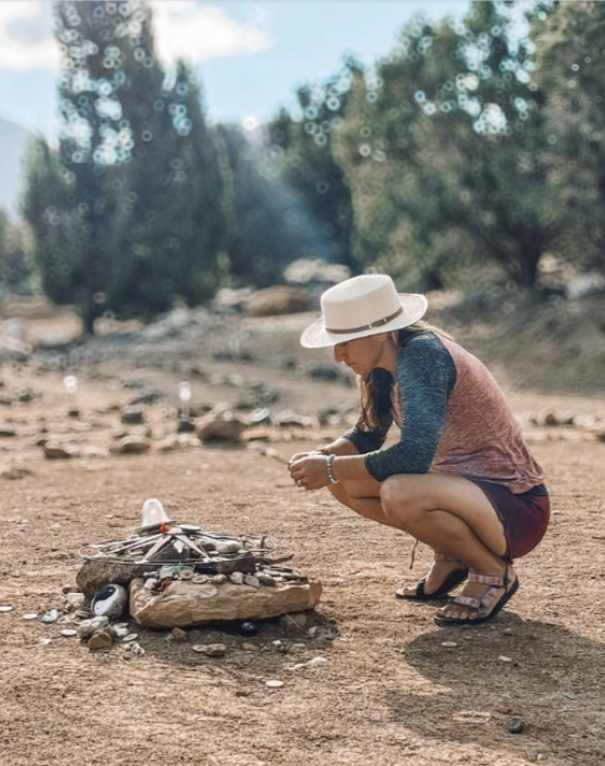 A silhouetted mountain range at sunset with orange sky in the background.