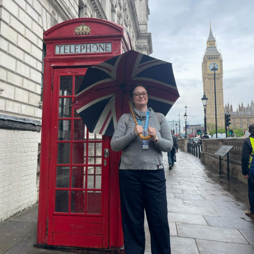 A tour guide stands next to a red telephone box in London with Big Ben in the background