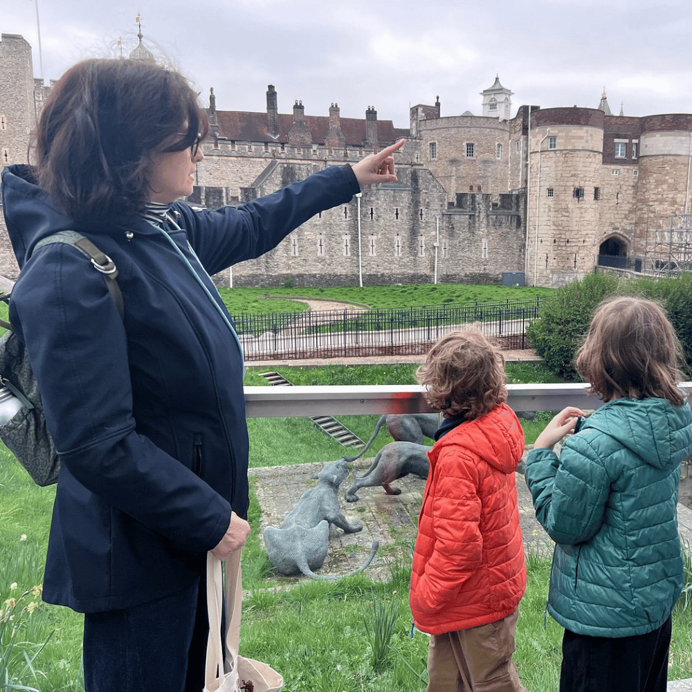 A tour guide points at the Tower of London, while two children look on