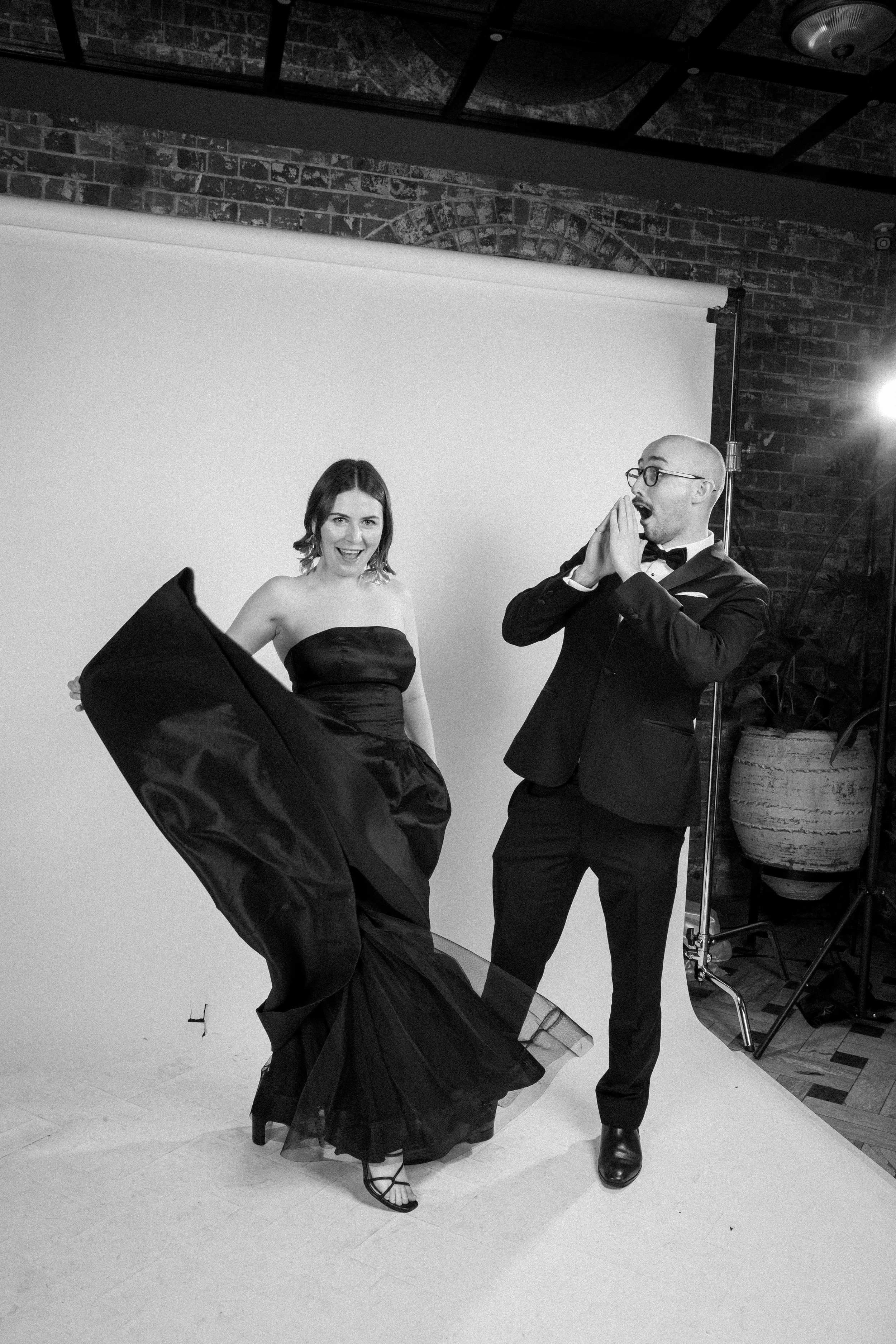 Candid moment of a woman dancing next to a man in a professional studio portrait setup.