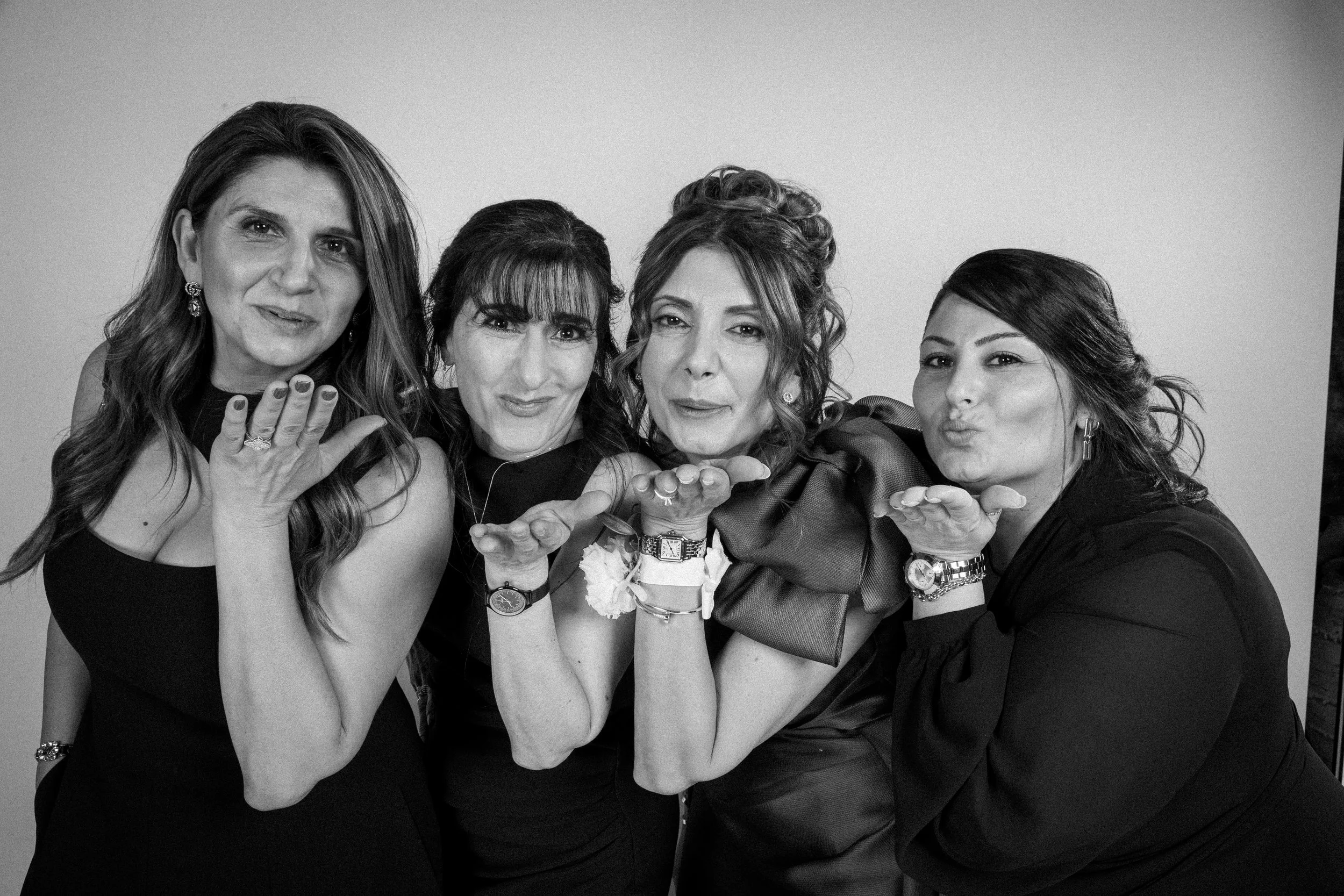 Four women blow kisses in a studio portrait photography session.