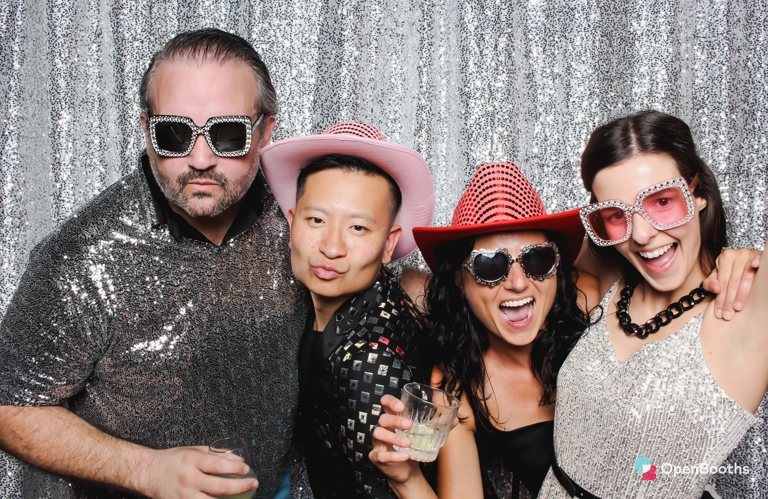 A group of people pose in an Open Booths photo booth with a sparkly silver sequin backdrop