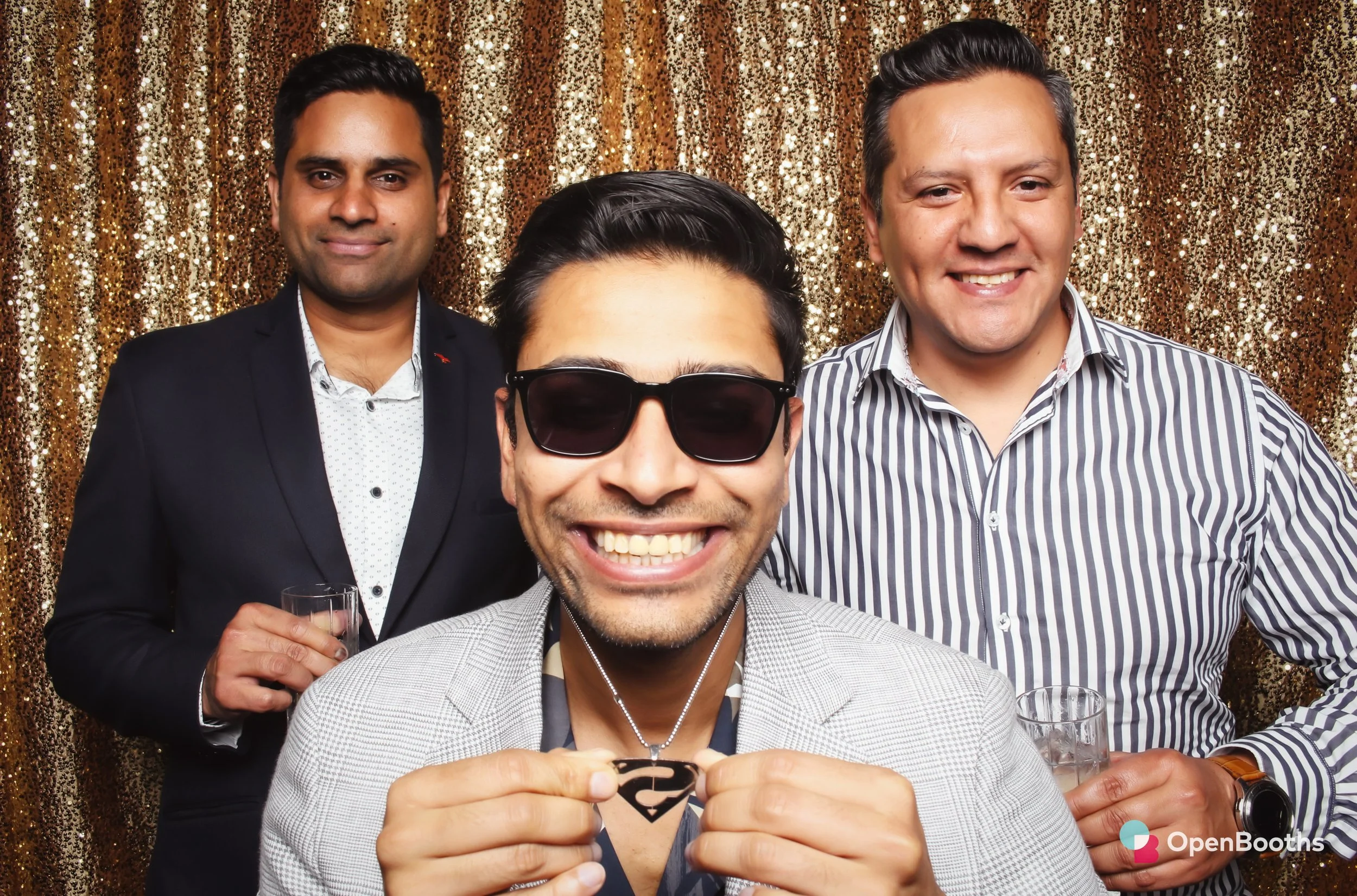 Three men pose in an Open Booths photo booth with a gold sequin backdrop