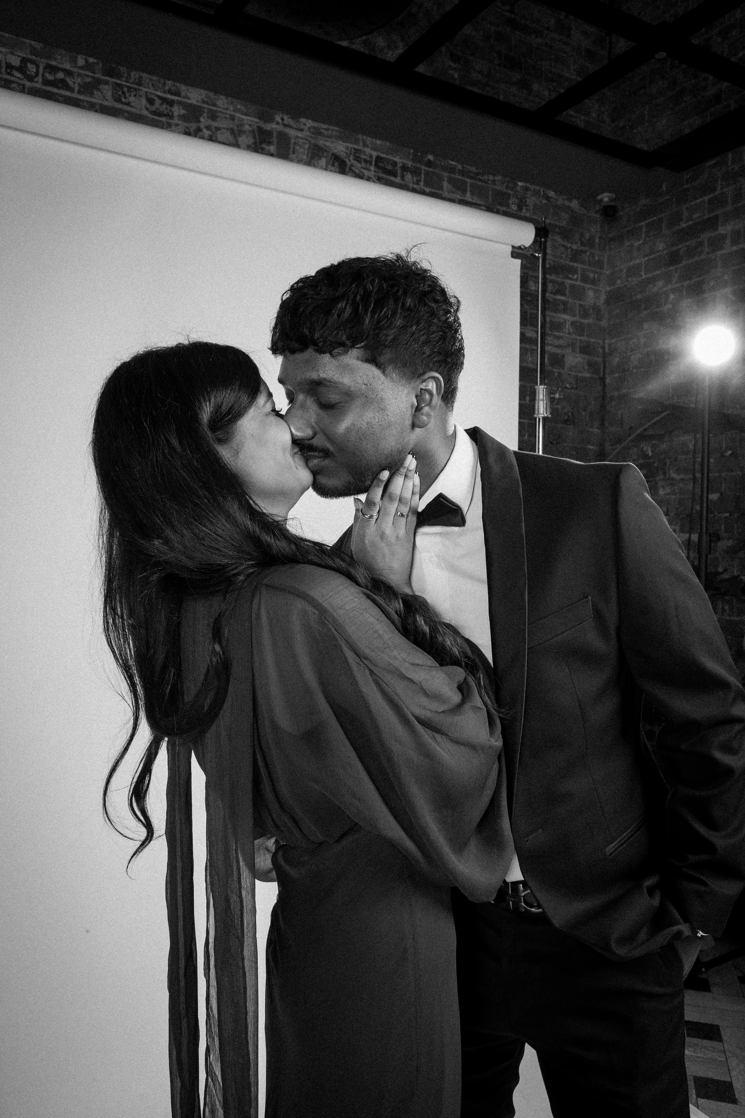 Romantic black-and-white portrait of a couple kissing at night during a Sydney wedding celebration.