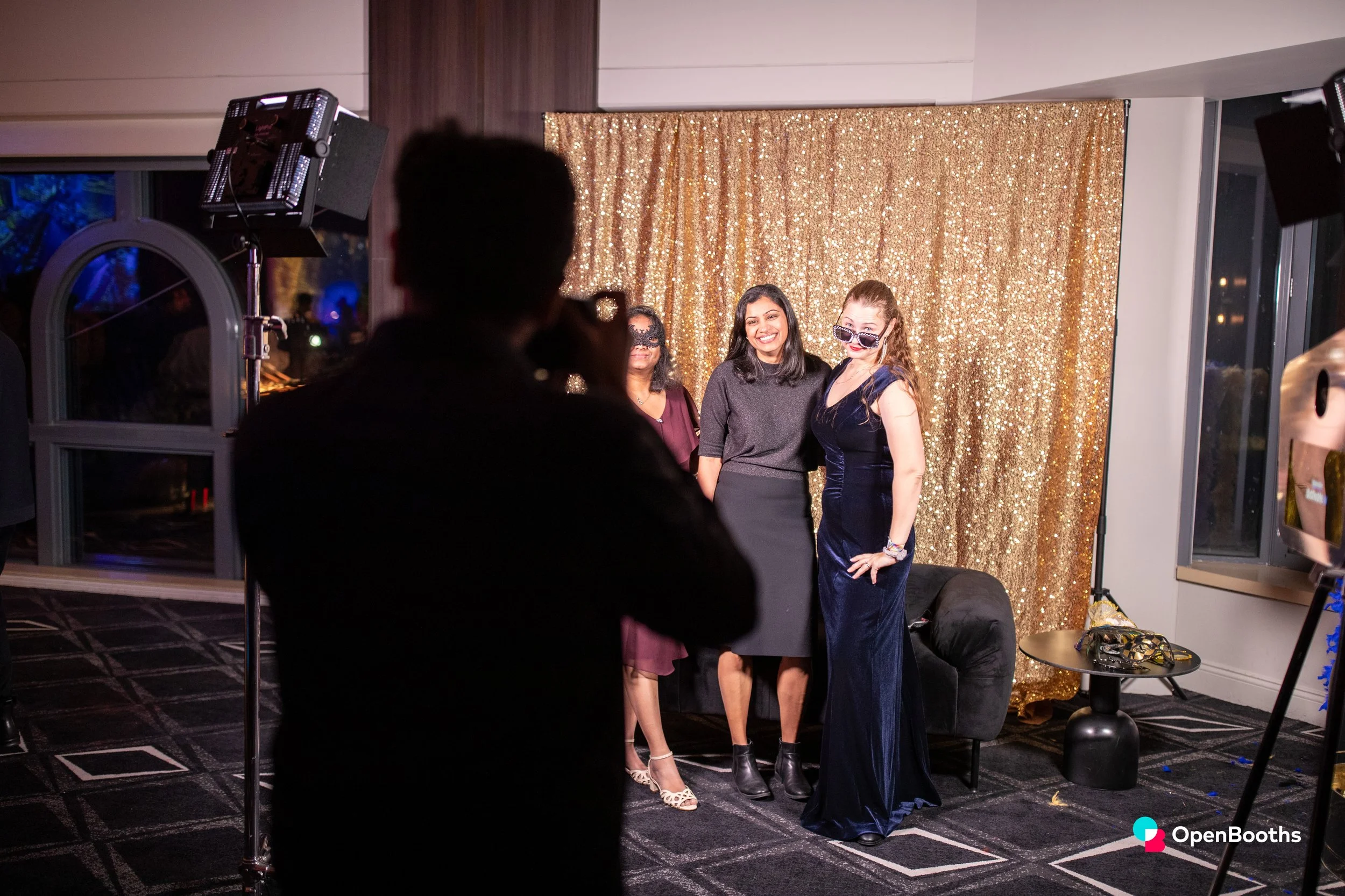 Women pose for a photographer in an open studio booth by Open Booths
