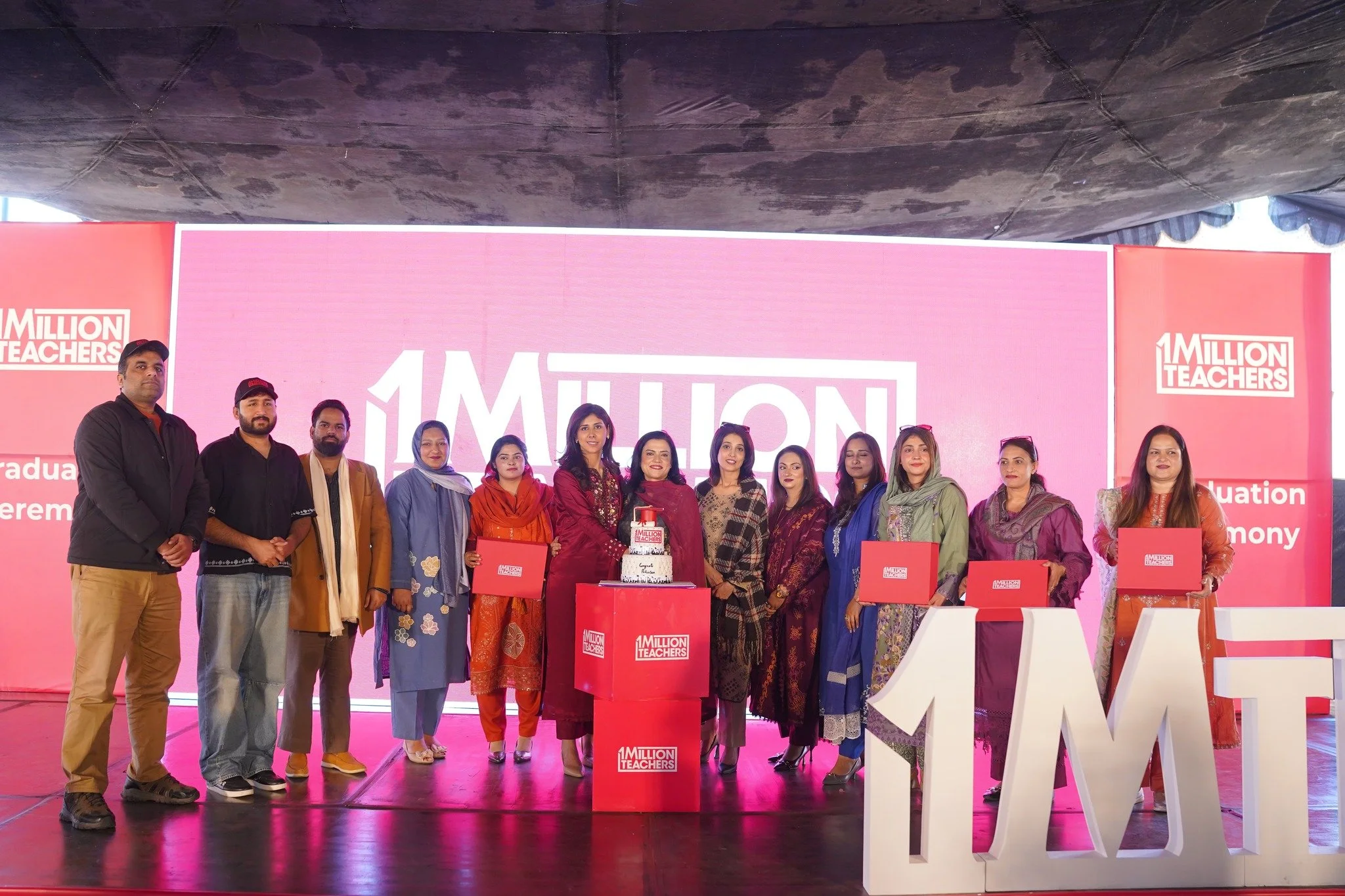 Three men standing in front of a logo that says "tuteria" on a wall with a geometric green and wooden background, inside a modern office space.