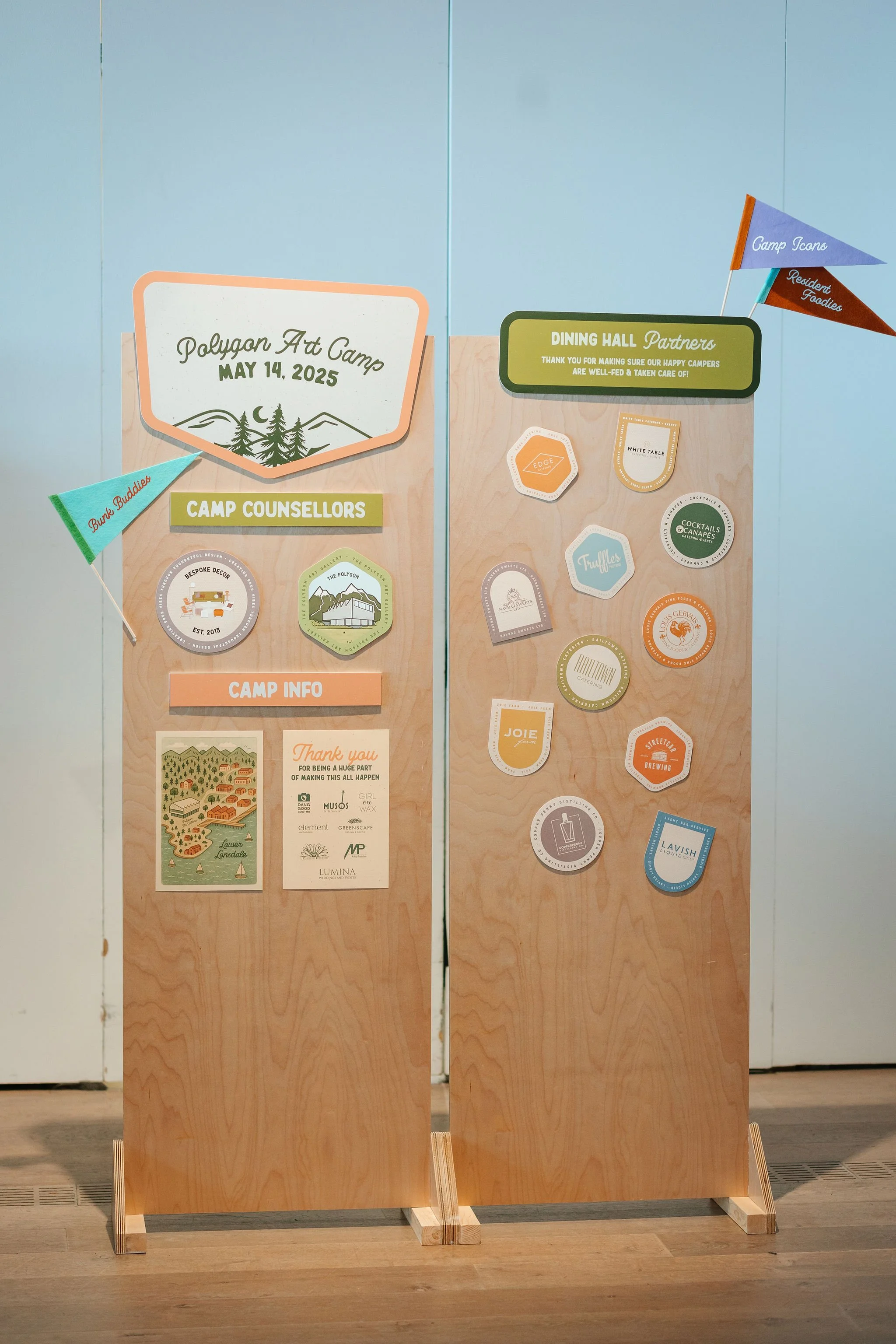 Information boards with camp details, including date May 14, 2025, with various stickers and flags for camp icons, partners, and counselors.