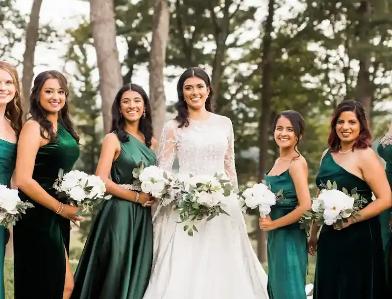 Bride and bridesmaids in emerald green velvet gowns holding silk floral bouquets featuring white peonies, roses, and eucalyptus greenery from the Emerson collection — Floréal Blooms NJ