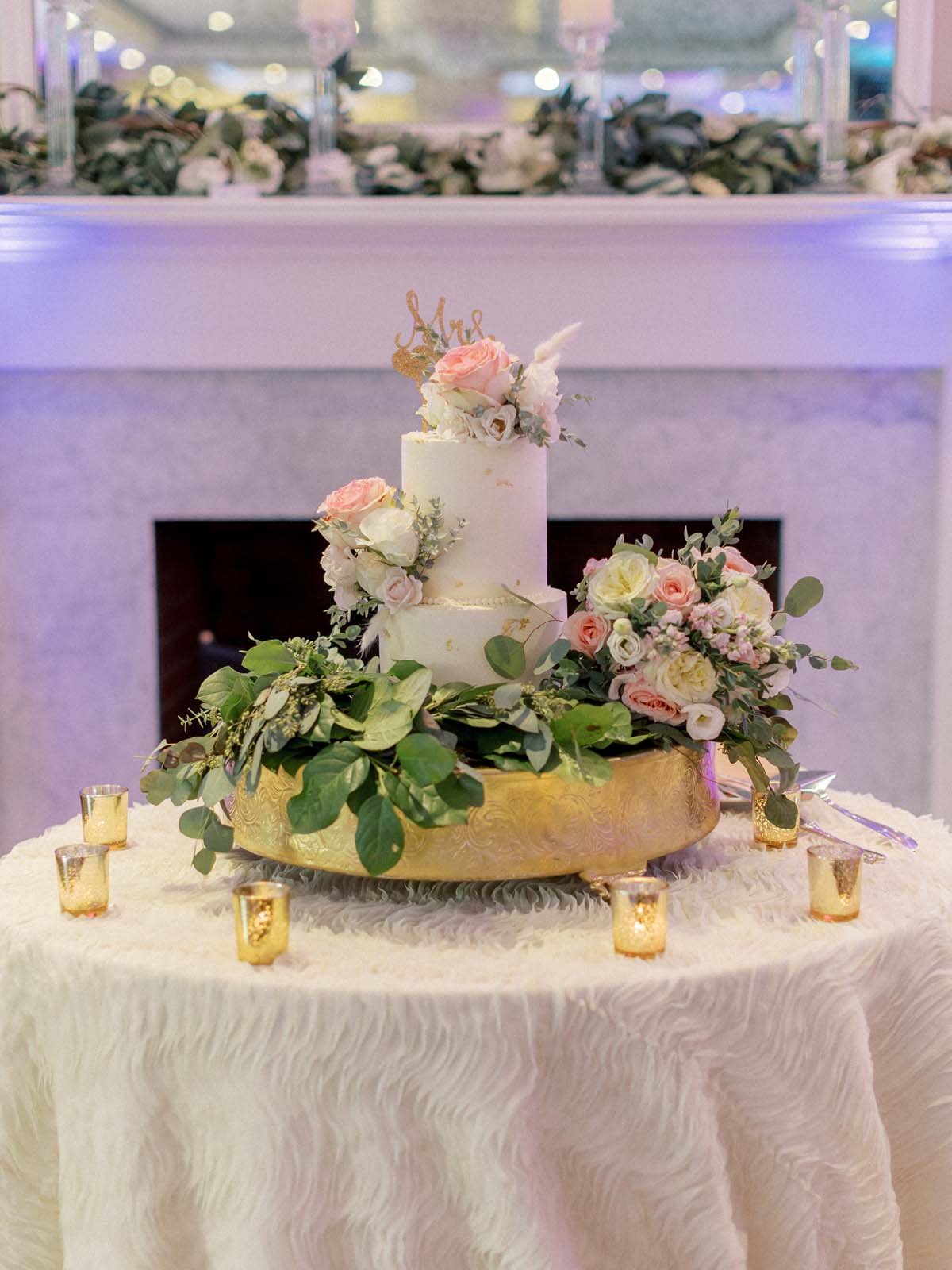 white wedding cake with greenery and pink flowers