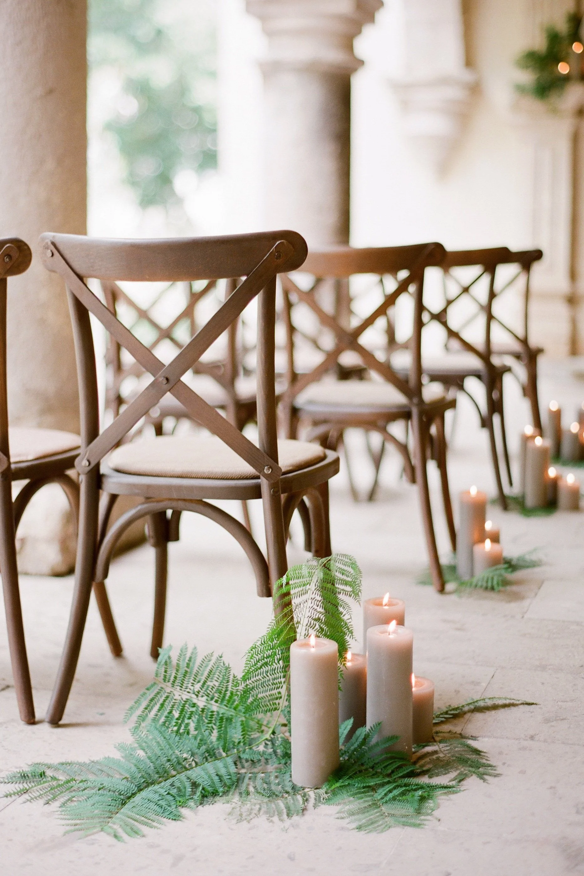 Chairs arranged for an event with candles and greenery on the floor.