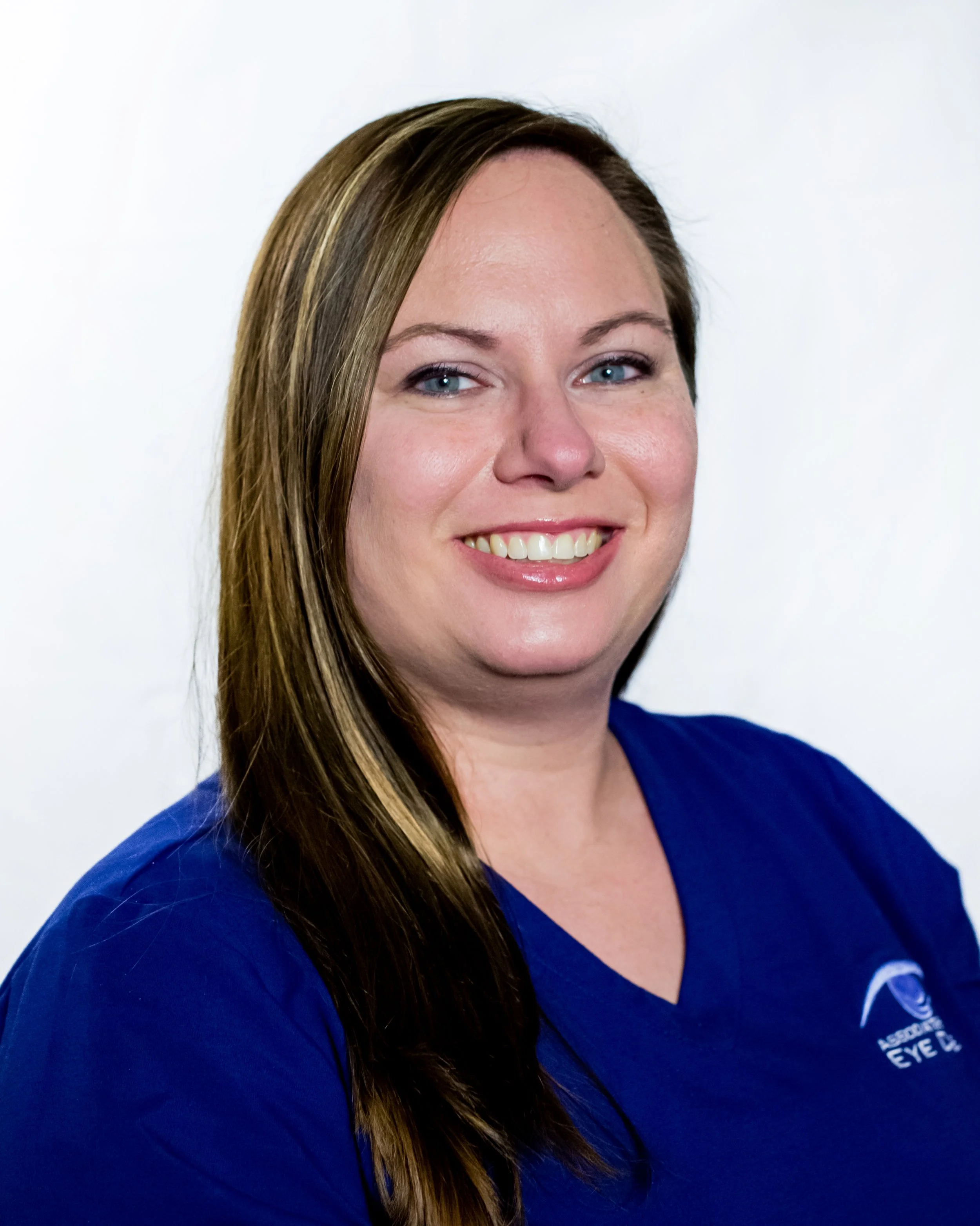 Portrait of a smiling woman with long brown hair wearing a blue shirt.