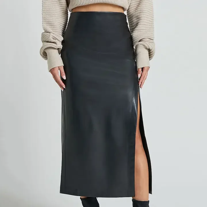A woman wearing a beige sweater and a long black leather skirt with a high slit on the side.