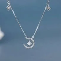 Silver necklace with a crescent moon and star pendant against a blue background.
