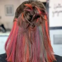 Back of woman's head showing colorful, multi-toned hair with pink, purple, and green shades styled in loose waves.