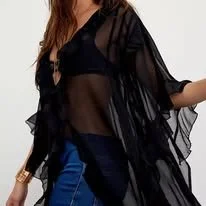 Woman wearing a black sheer cover-up over a black top and blue jeans