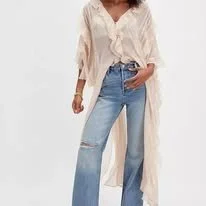 Person wearing a white, long-sleeved blouse and light blue ripped jeans standing against a plain white background.