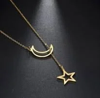 Gold necklace with a crescent moon pendant and a star pendant against a dark background.