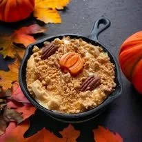 Pumpkin dump cake topped with pecans and mini pumpkin-shaped candies, surrounded by autumn leaves and a pumpkin.