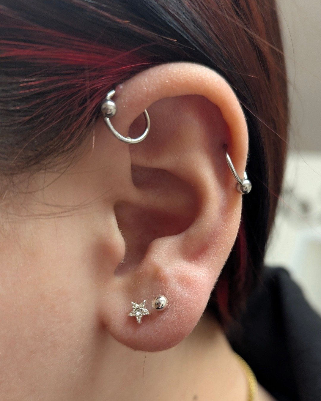 This client came in to see me after getting this set of piercings (first photo) about a year ago from another piercer. They had asked for an industrial piercing (which is two piercings connected by a single piece of jewelry, usually a straight barbel