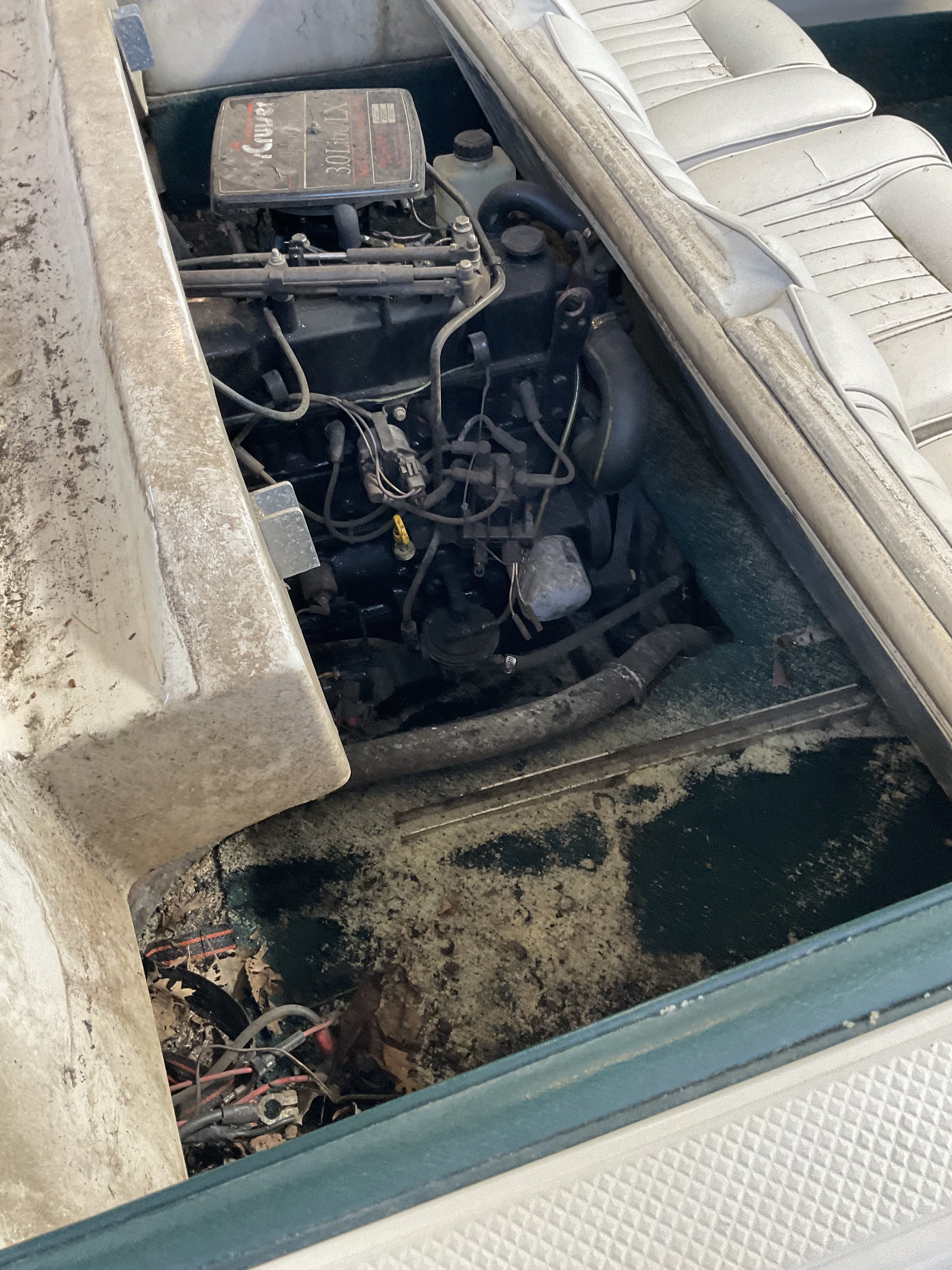 Boat engine compartment with an older inboard motor, visible wiring, and a worn interior.