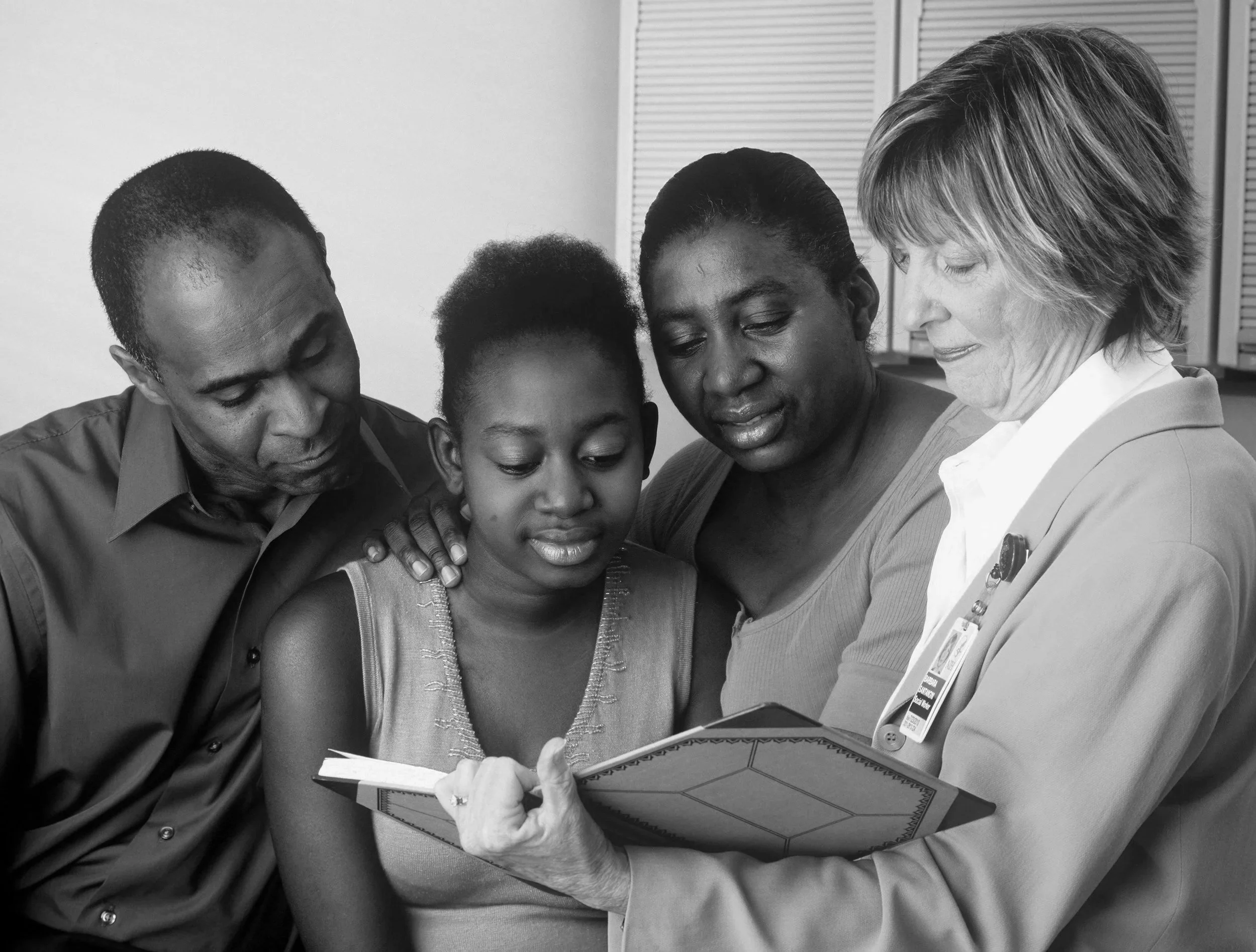 Black and white photo of family being shown a book family therapy Riverside CA