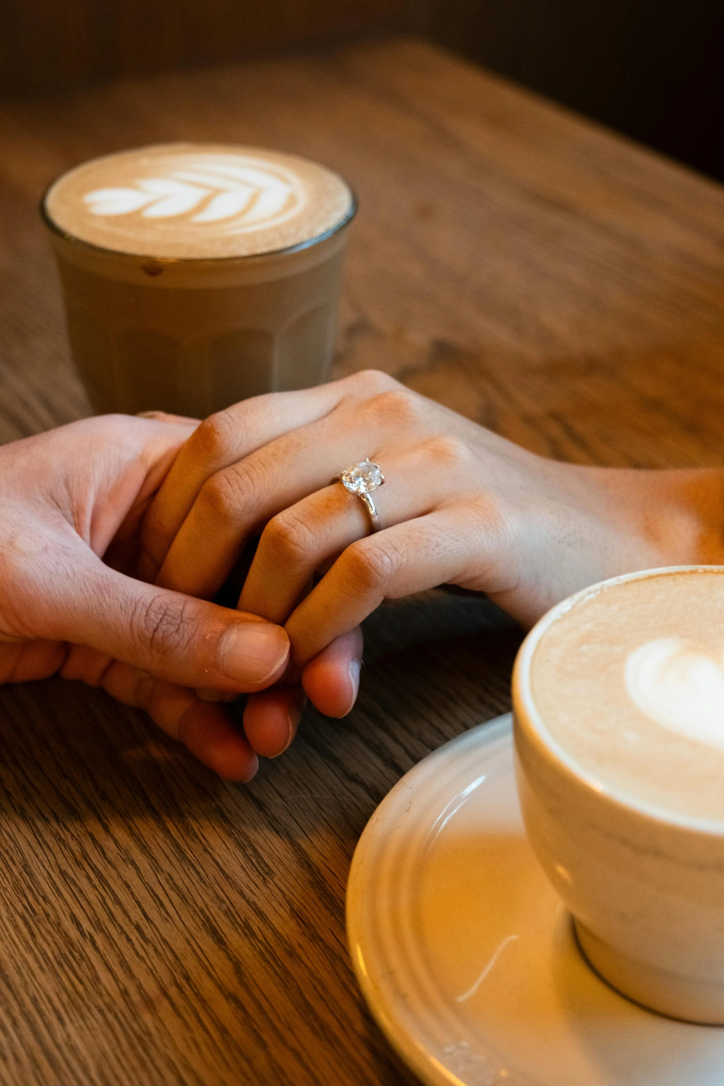 couple holding hands across a table while sharing coffee
