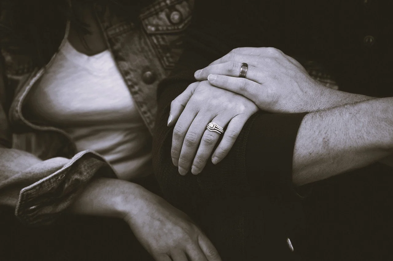 close up of a man and woman's hands with wedding rings