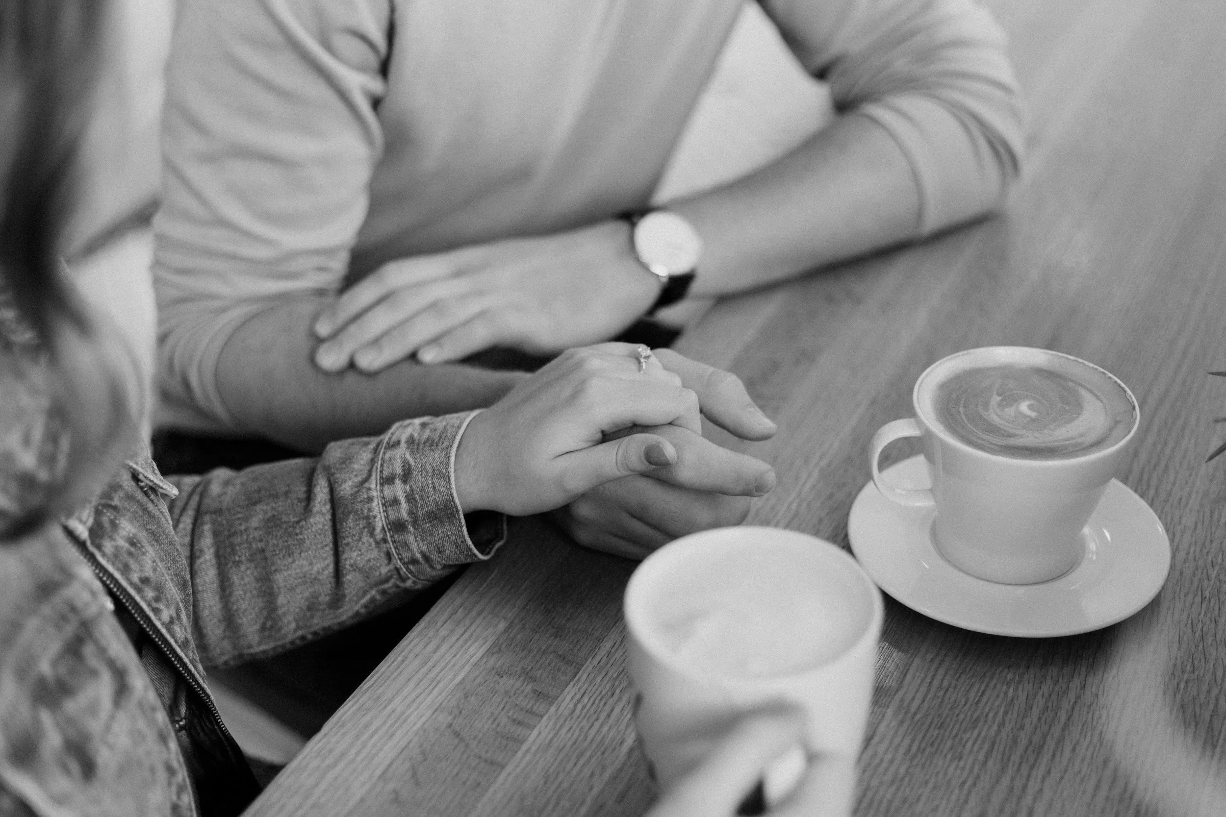 Black and white photo of couples having coffee and holding hands