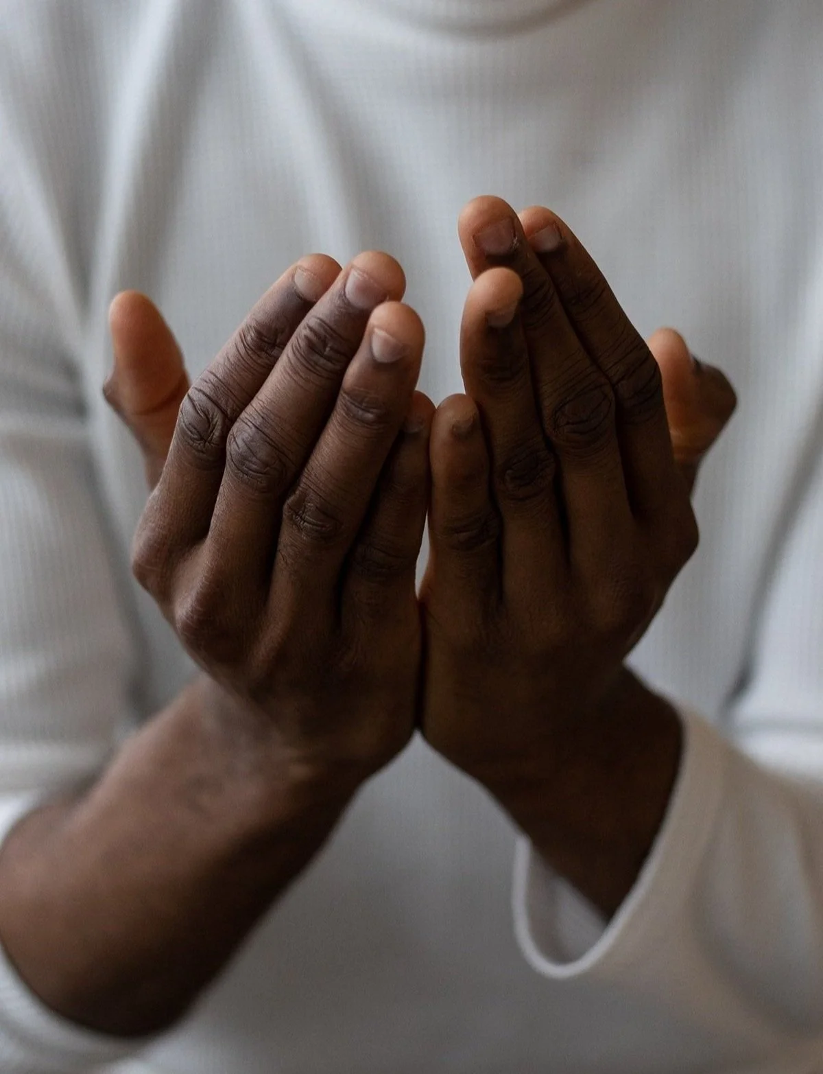 Close up of a person's hands near their chest as if preparing to pray. This is for interfaith couples counseling in California