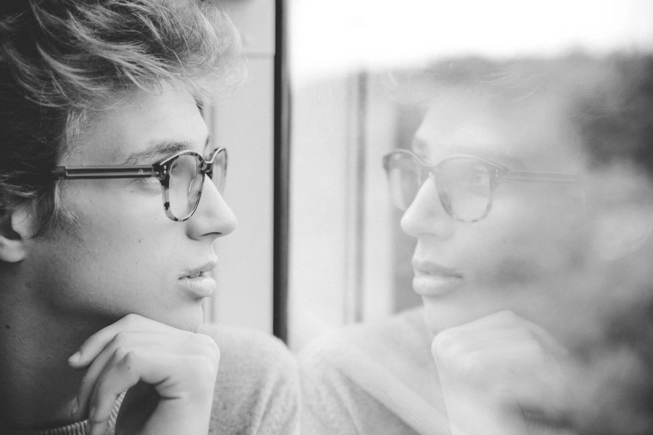 Black and white photo of man looking at himself