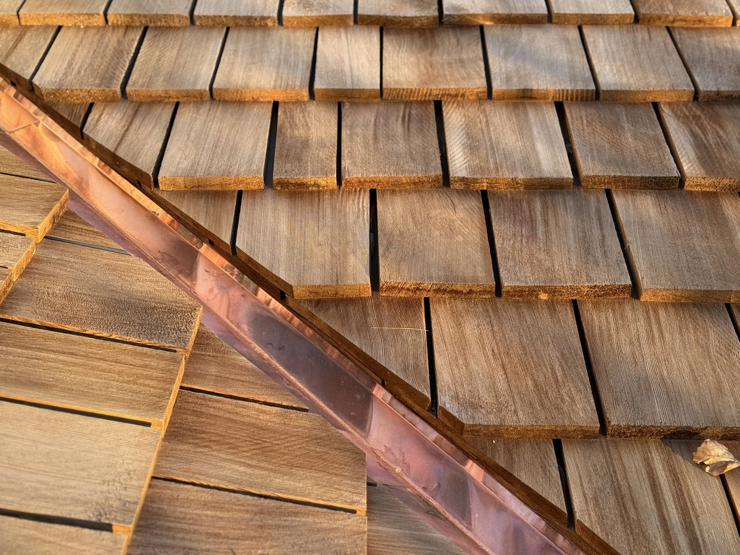 Tapersawn cedar shake shingle roof and copper valley installed by Petoskey Roofing overlooking Walloon Lake