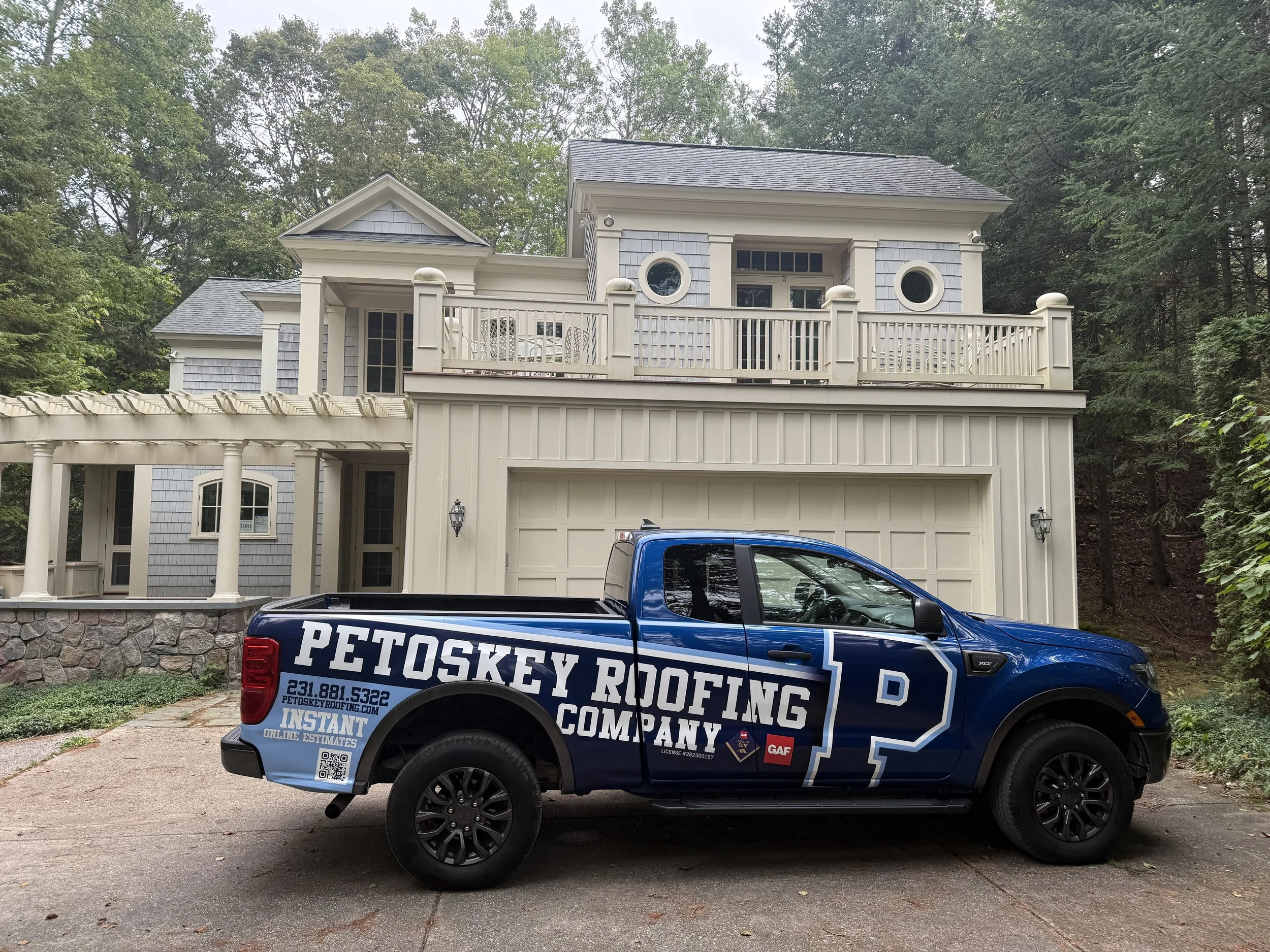 Petoskey Roofing Company truck parked in front of a custom home in Northern Michigan