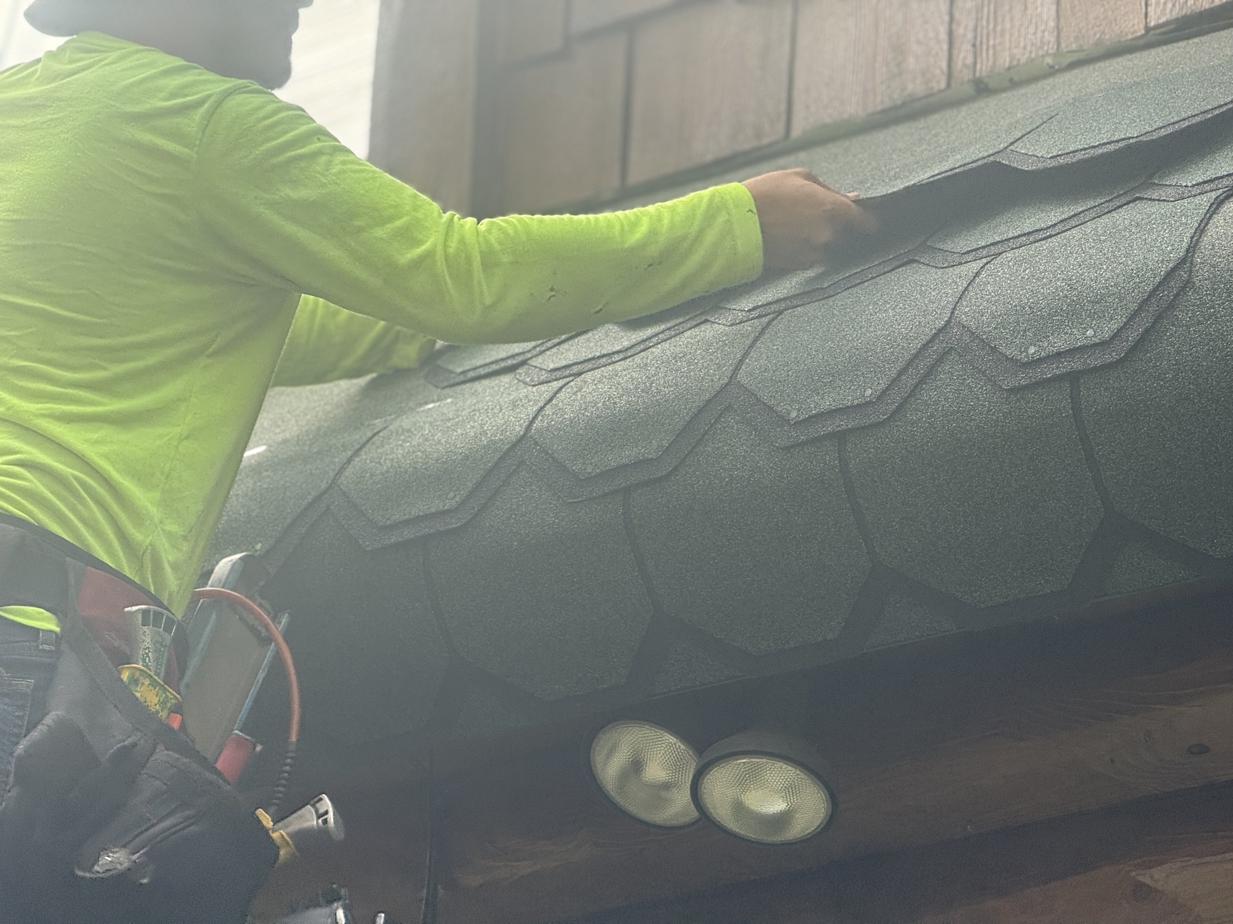 Roofer installing designer Certainteed Sherwood Forest shingles on log cabin-style home in Charlevoix Michigan