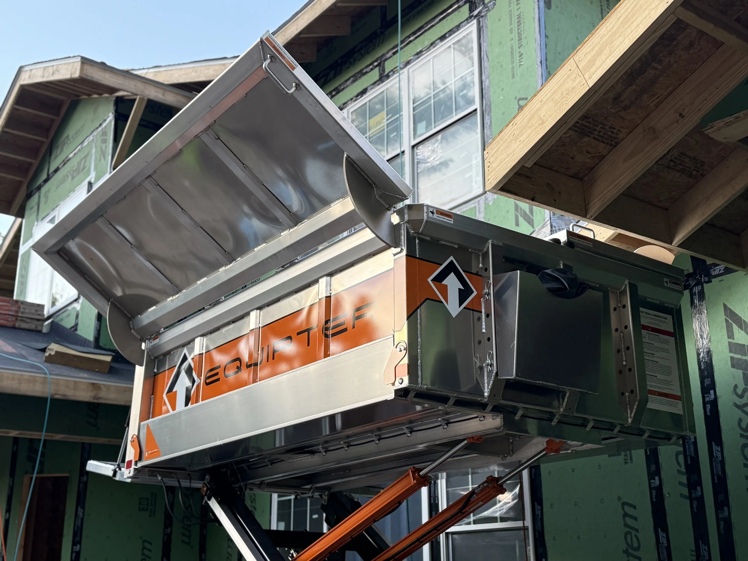 Equipter roofing trailer raised to roofline for clean tear-off and debris control on new construction project