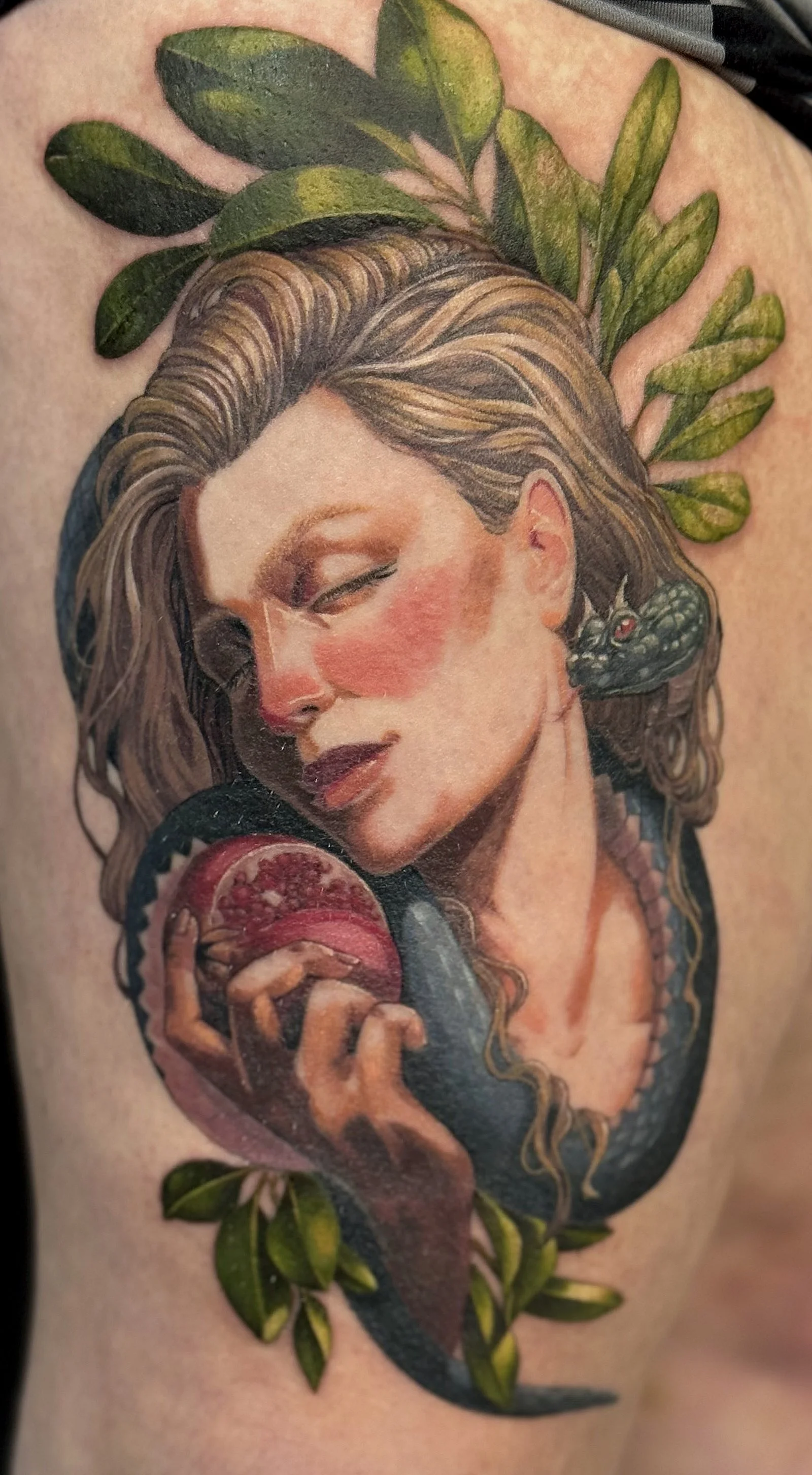 A tattoo of Lilith holding a pomegranate in the Garden of Eden with the Serpent wrapped intimately around her