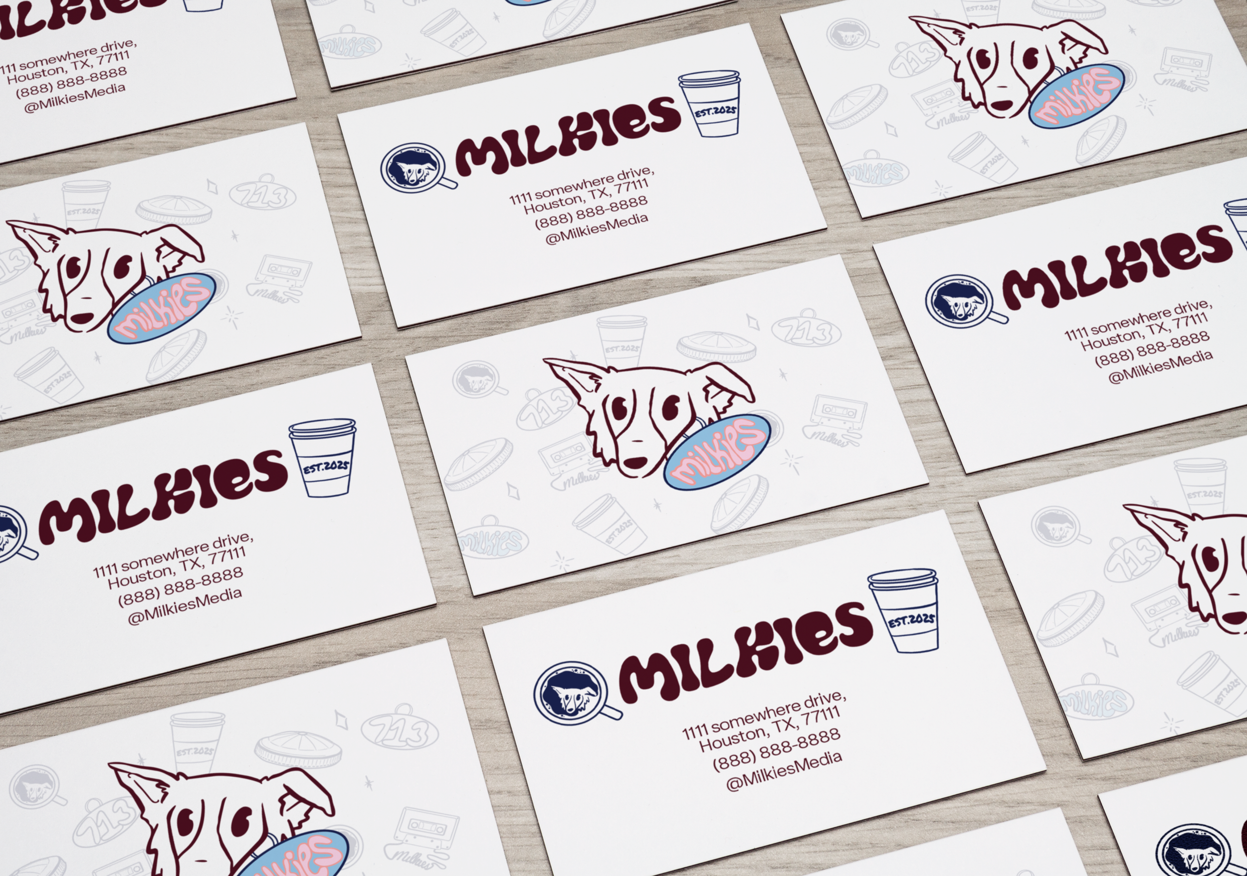A collection of business cards for a company named Milkies, featuring a cartoon dog and illustrations of coffee, snacks, and other items, on a wooden surface.