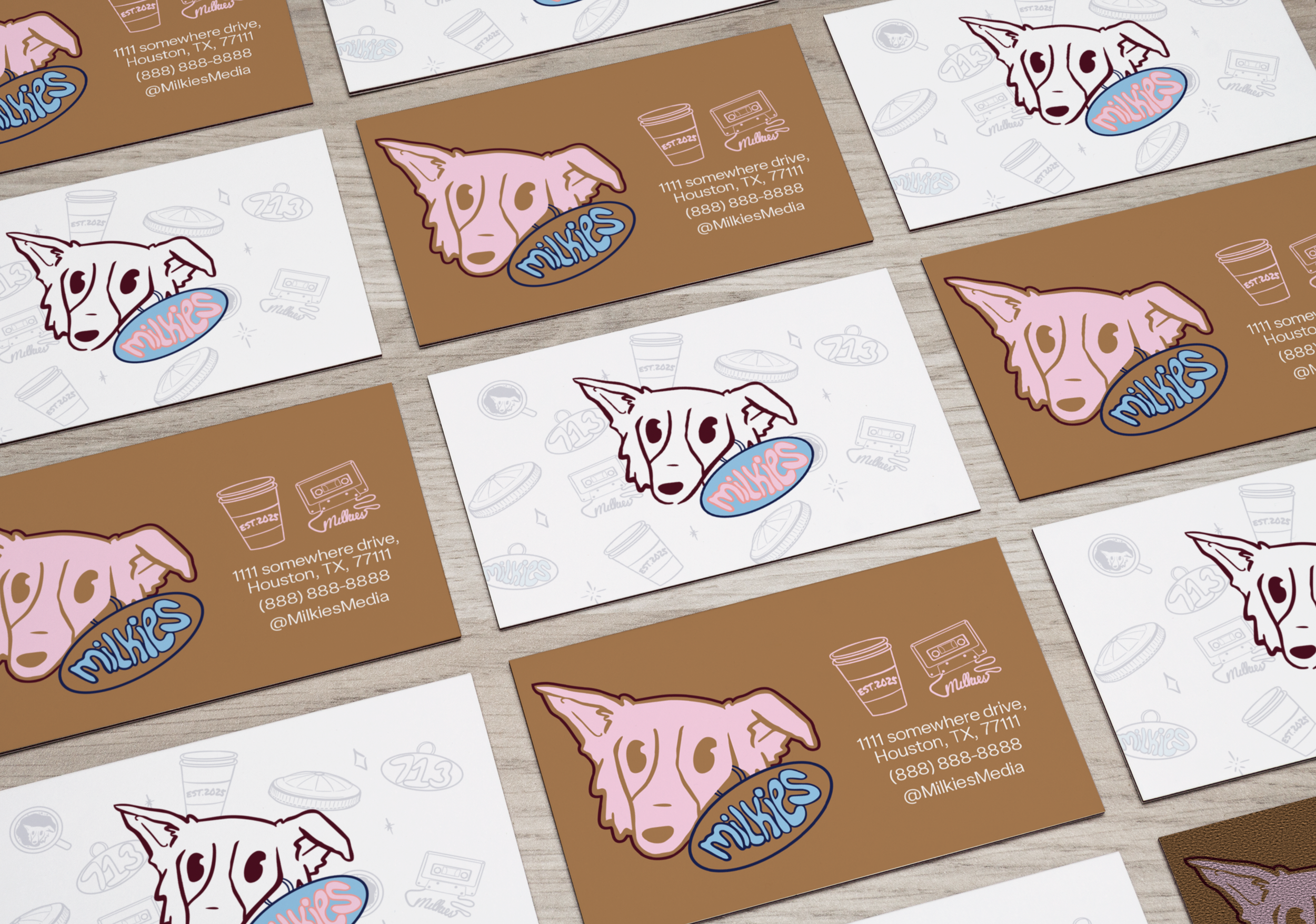 A collection of business cards with a dog logo, featuring pastel pink and blue colors on different background colors, including white and brown, laid out on a wooden surface.