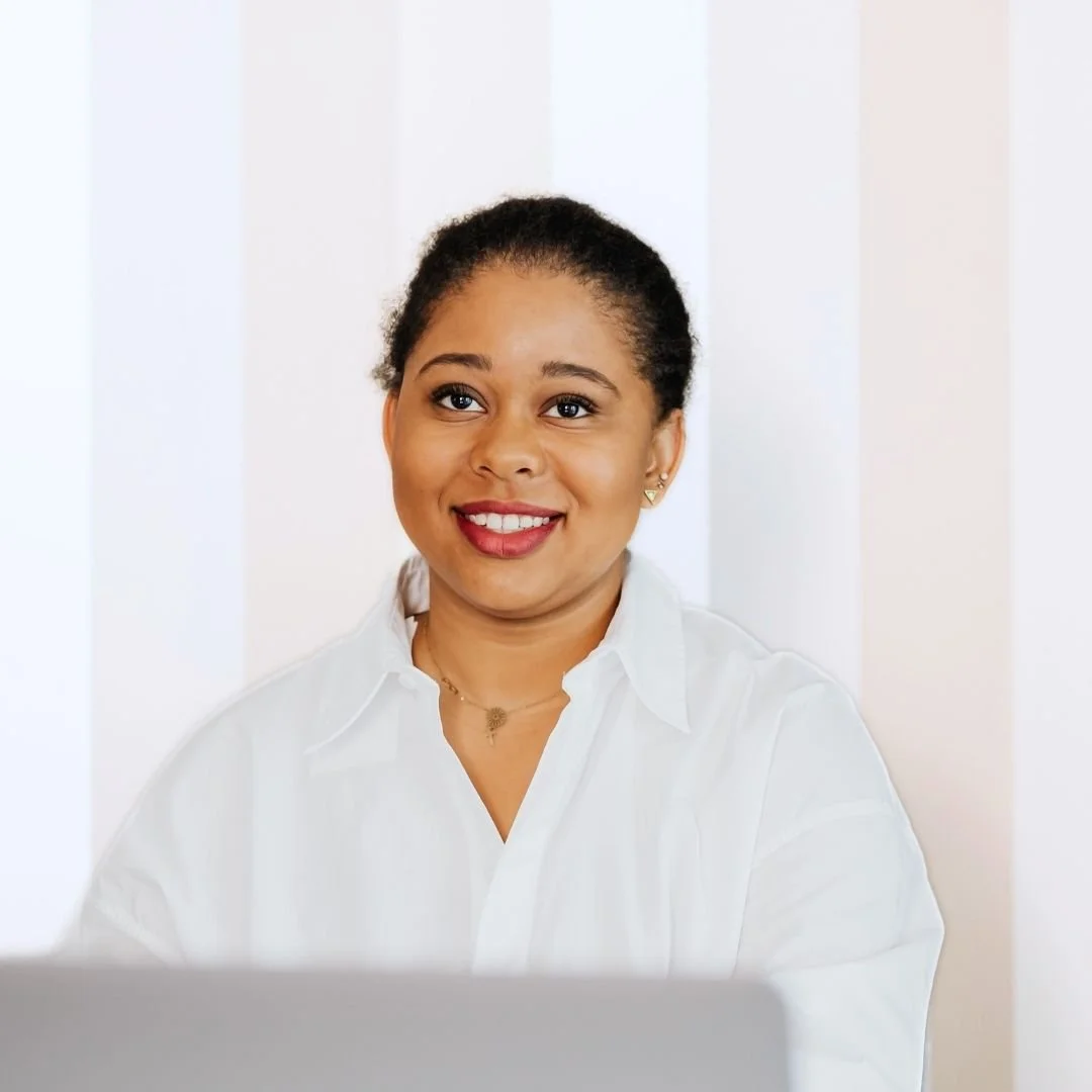 A woman with short, curly hair and a white collared shirt, smiling at the camera.