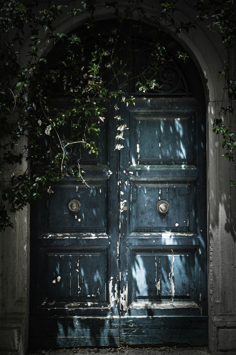 A teal arched doorway framed by greenery