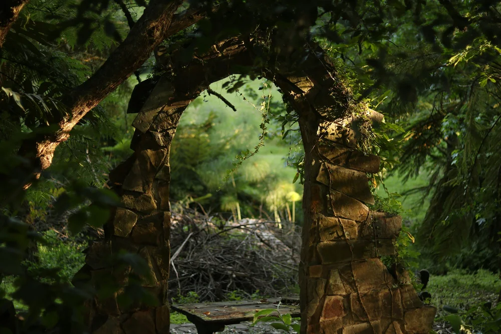 A moss-covered stone archway glowing with light in a forest