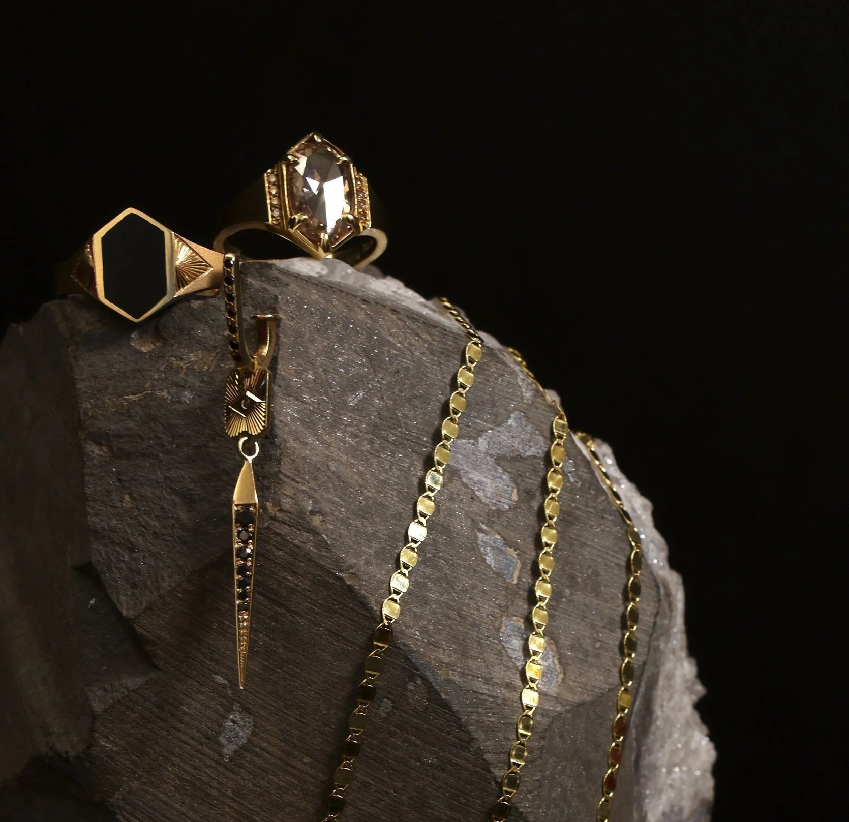 yellow gold bracelets, earrings and signet rings presented on a large stone