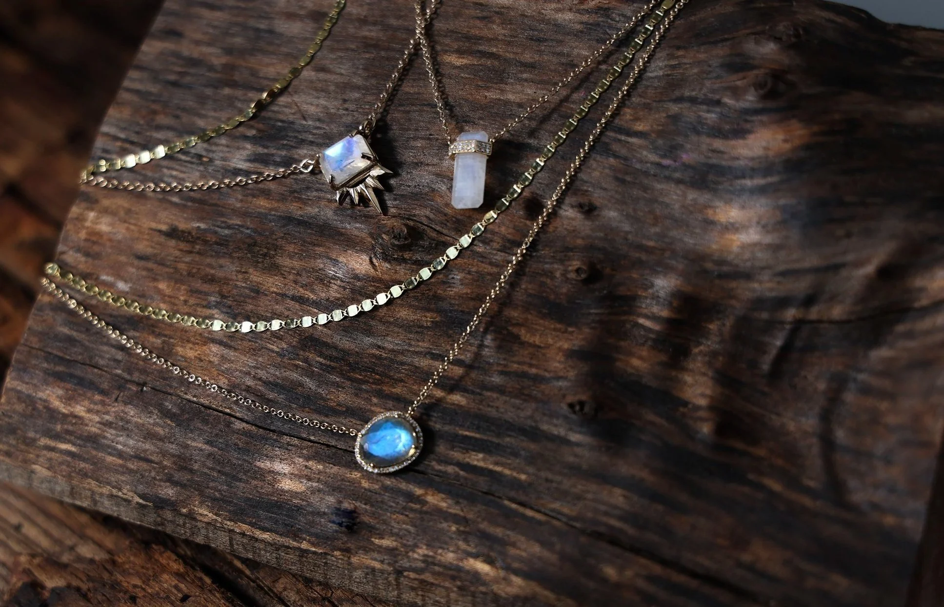 gold necklaced with moonstones laying on dark wood