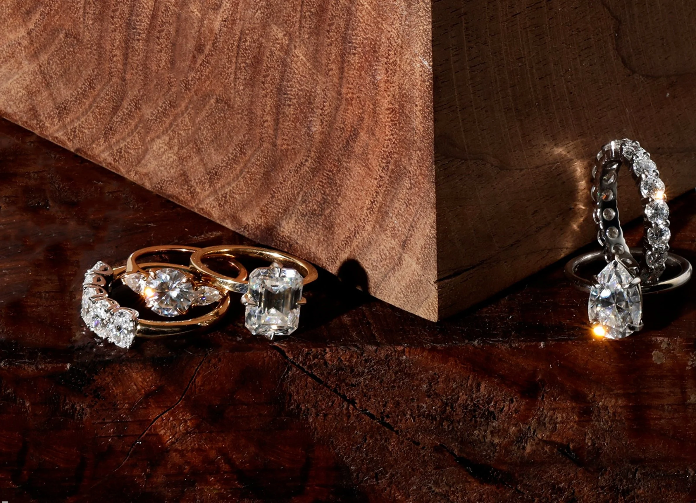 3 yellow gold and white diamond engagement rings presented on blocks of wood
