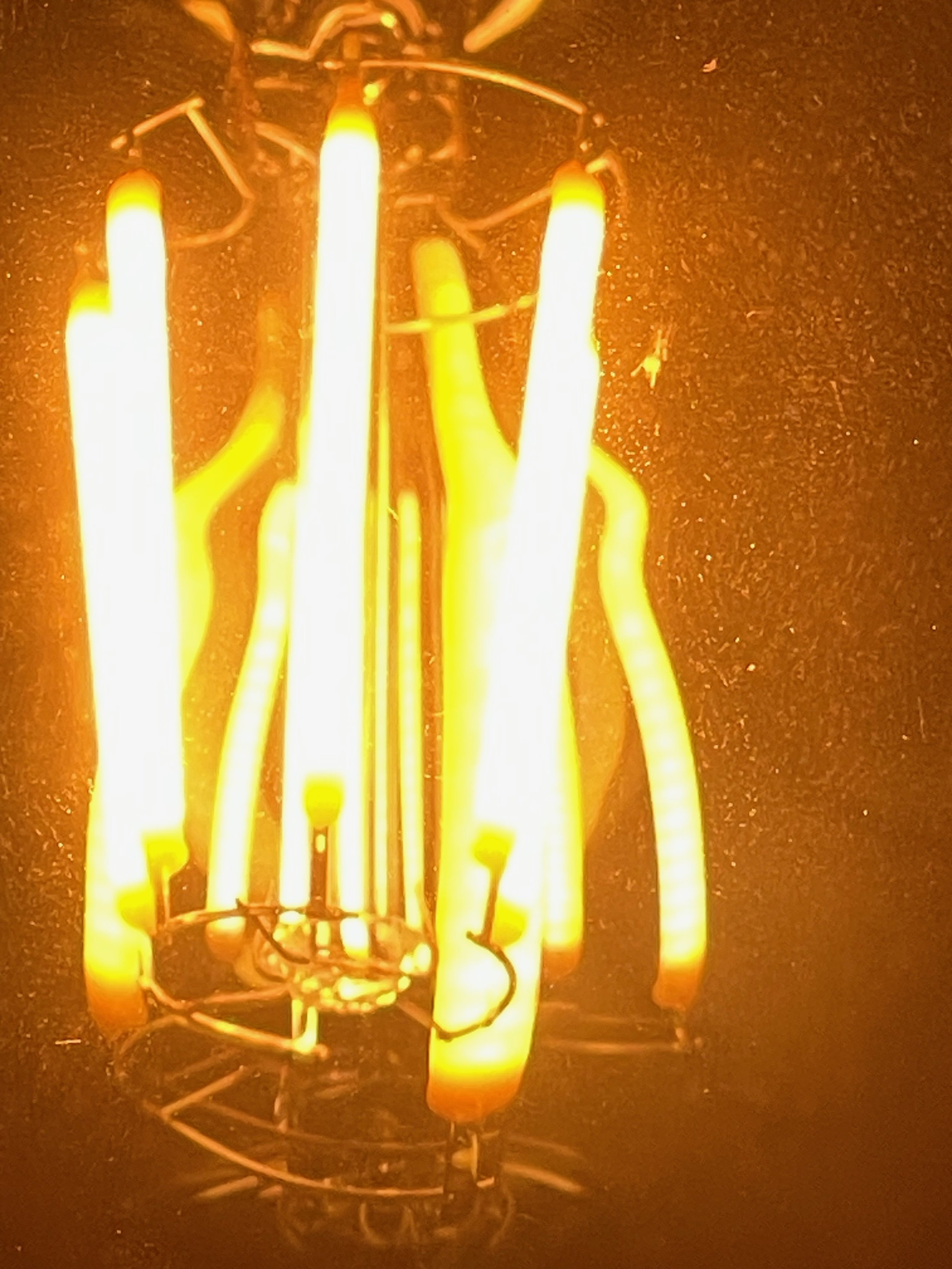 Close-up of an illuminated vintage light bulb with glowing filament.